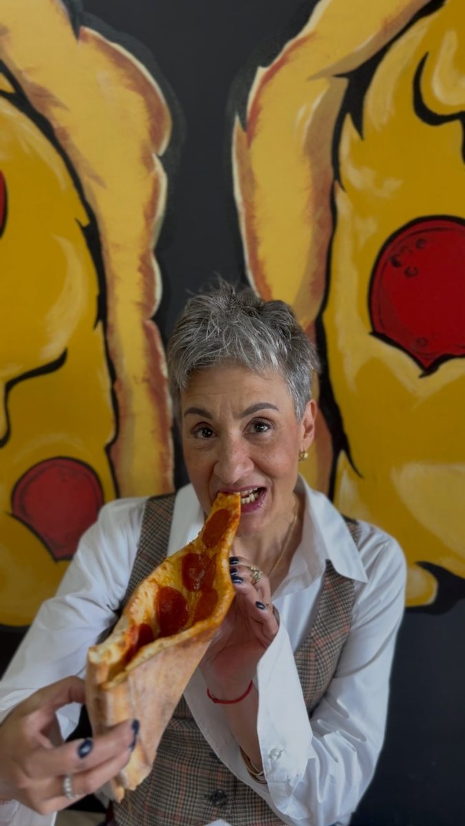Guest eating a slice in front of the mural
