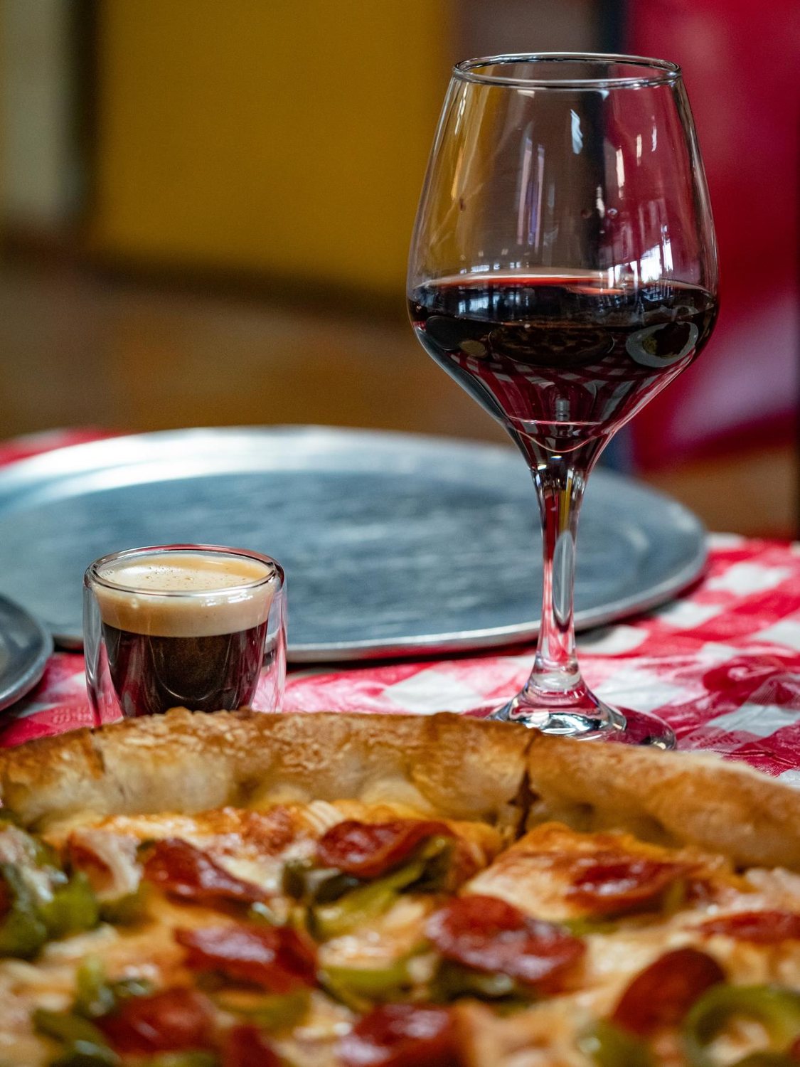 Pizza pie with a glass of red wine and an espresso