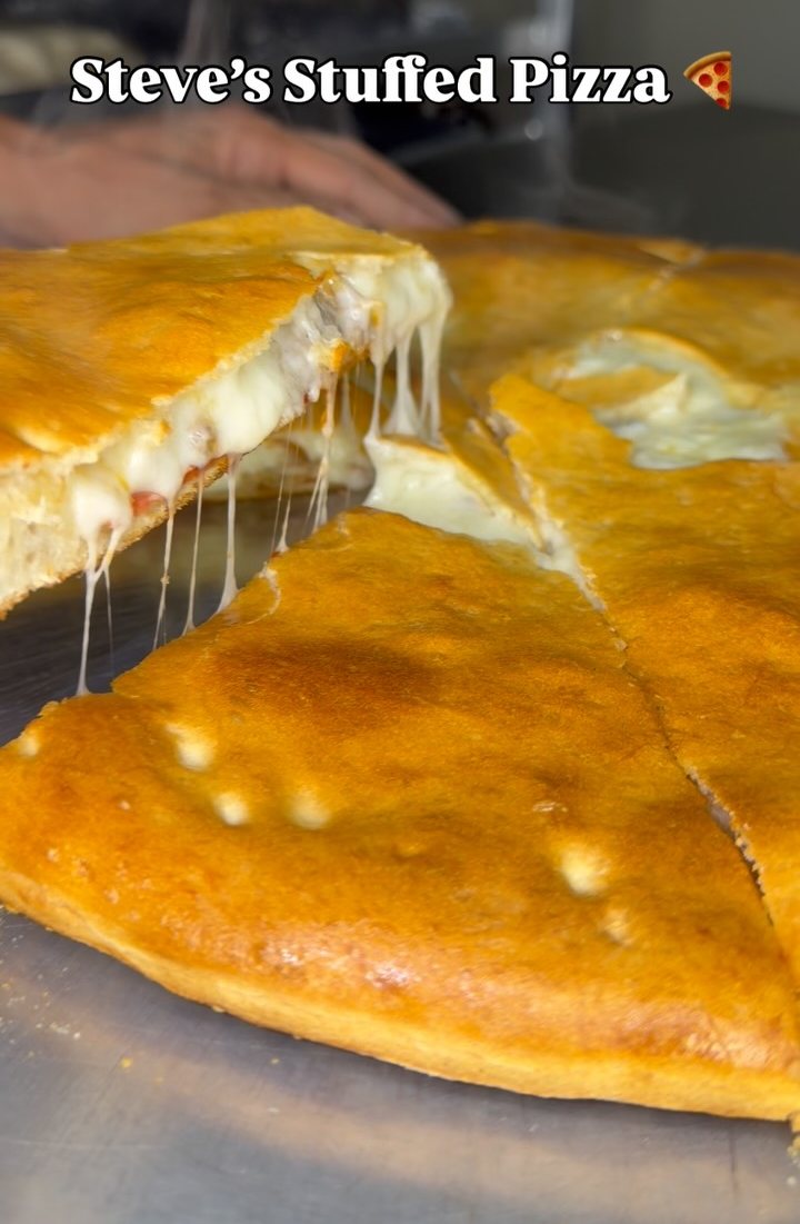 Stuffed pizza, cut open, cheese stretching between the slices
