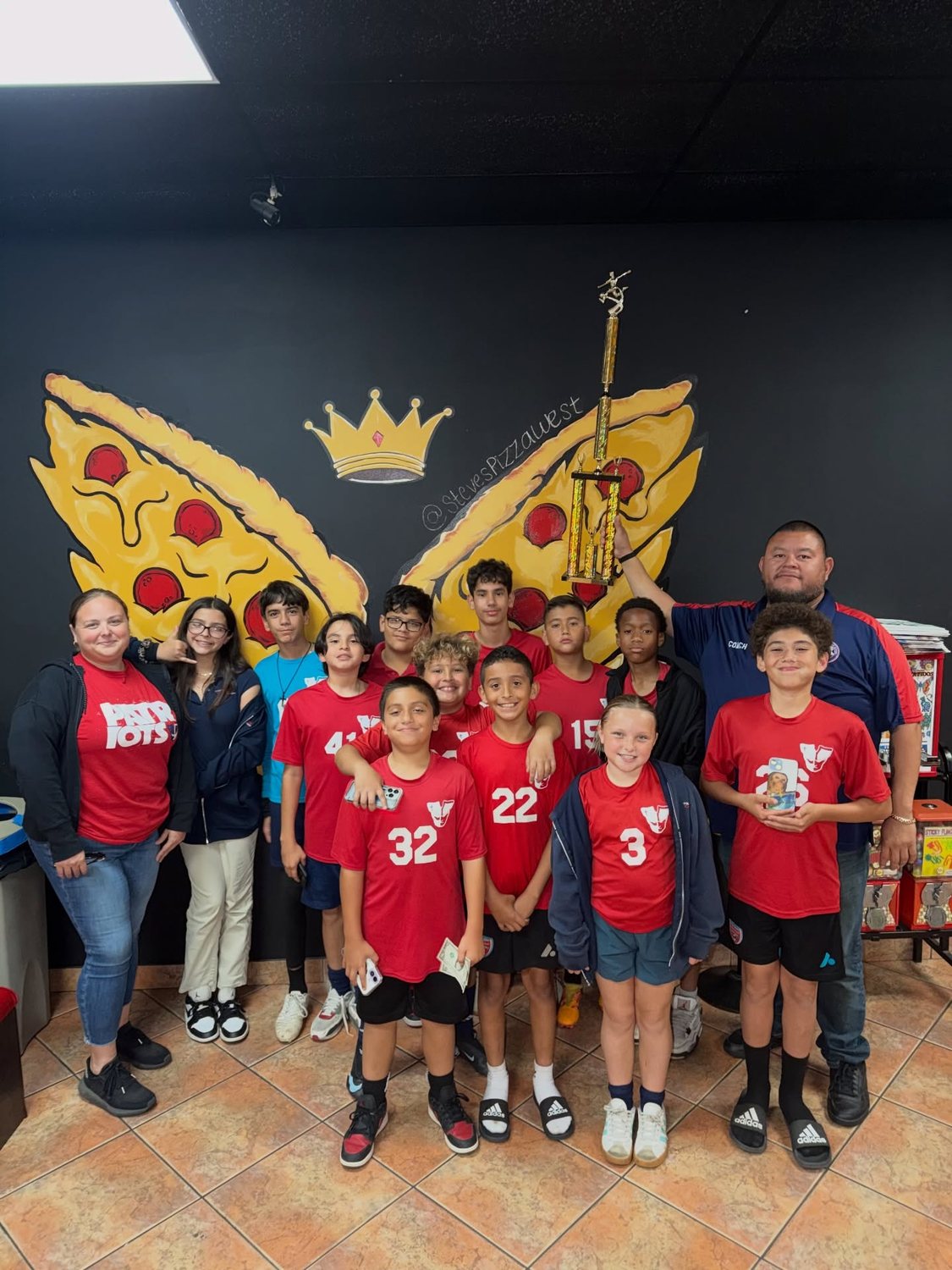 Youth sports team celebrating at the painted pizza and wings mural with a crown